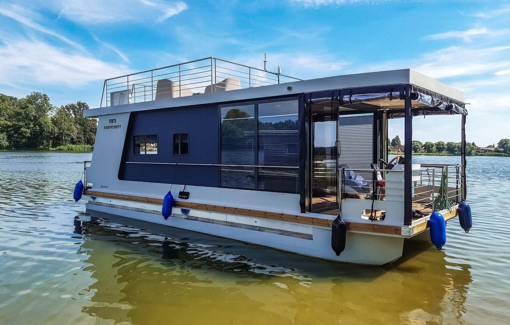 A houseboat with a covered deck, a small cabin, and a lounge area with seating.