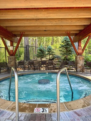 Une piscine avec un panneau indiquant qu’il est interdit de plonger, un indicateur de profondeur indiquant 1 mètre (3 pieds et demi), et une terrasse en bois avec des chaises et un mur en pierre.
