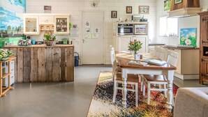 A spacious kitchen with a wooden island, white cabinets, and a dining area with a table and chairs.