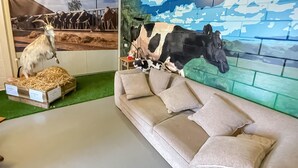 A room with a beige sofa, a green carpet, and a mural of cows.