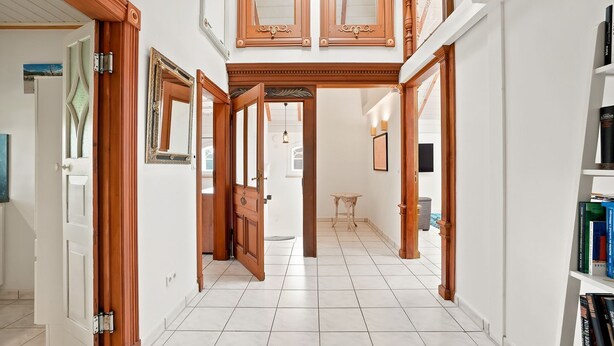 A hallway with wooden doors, a tiled floor, and a bookshelf with books.
