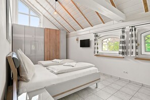 Ein modernes Schlafzimmer mit einem Bett, einem Fernseher und einem Fenster mit Vorhängen.