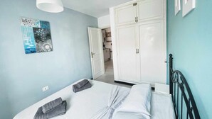 A bedroom with a bed, a wardrobe, a hanging light, and a wall art piece. - Semicorchea Corralejo Center iRent Fuerteventura (Corralejo)