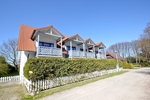 Ein zweistöckiges Haus mit rotem Ziegeldach, weißen Außenwänden und einem weißen Zaun.