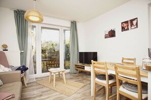 Un salon confortable avec un téléviseur, des meubles en bois et une vue sur l’extérieur.