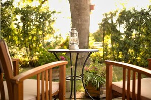 A wooden table with a metal frame and a lantern on top, surrounded by two wooden chairs with cushions. - Cozy vacation apartment near the harbor - FeWos am Hochzeitsberg FeWo 08 - FeWos (Breege)