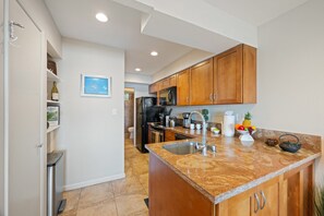 A modern kitchen with wooden cabinets, a granite countertop, stainless steel appliances, and a small island with a sink.