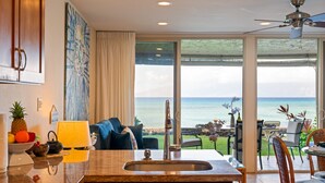 A kitchen with a large island, a view of the ocean, and a dining area with outdoor seating.