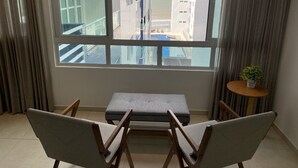 A room with a view of a beach, a small table with a plant, and a bench. - Bela Hospedagem - Vista piscina e mar (João Pessoa)