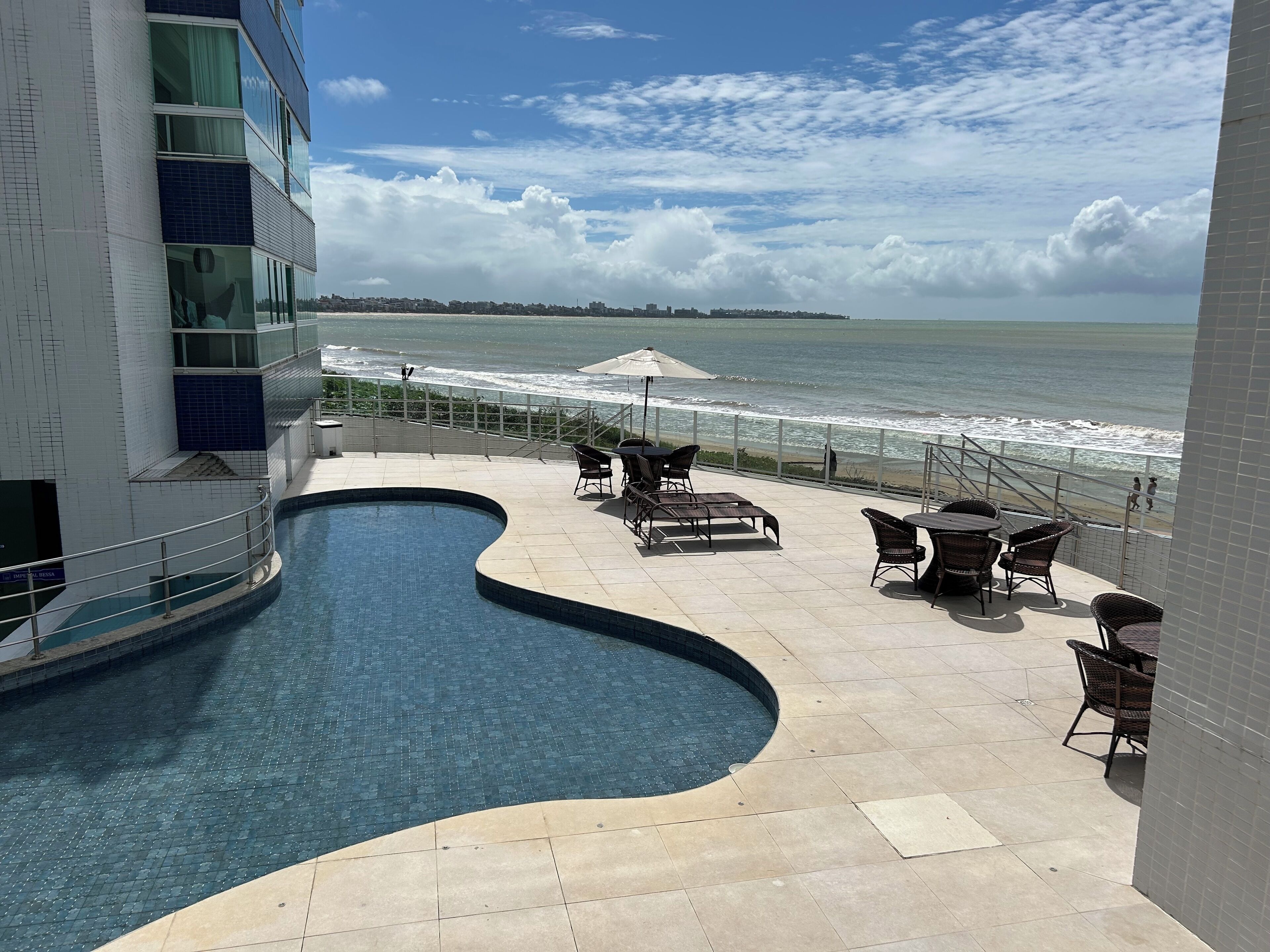 Una piscina al aire libre, sombrillas, sillones reclinables de piscina
