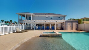 Une maison à deux étages avec une piscine, un patio couvert avec des chaises et un espace clôturé.