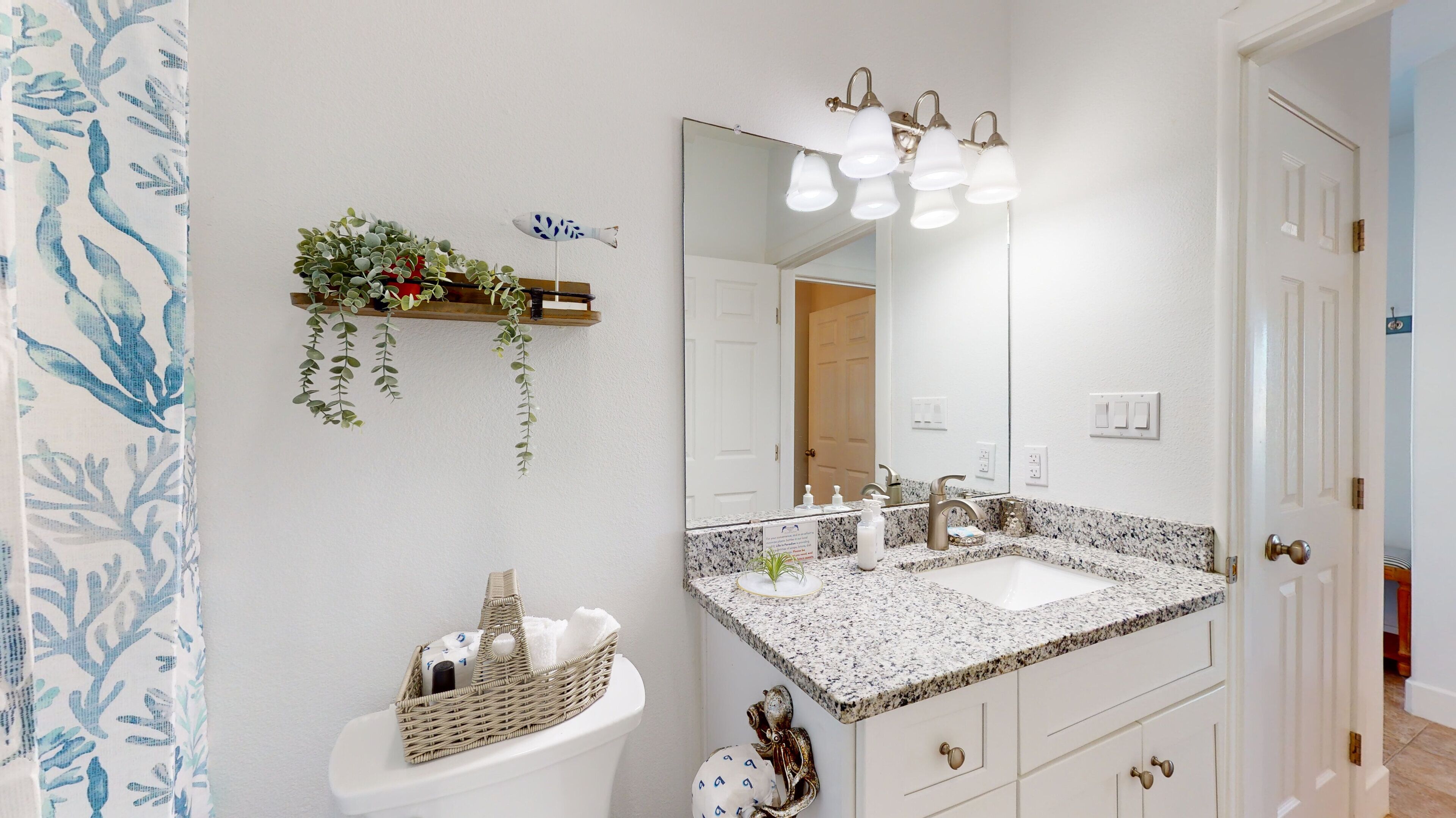 A bathroom with a white sink, a large mirror, and a granite countertop.