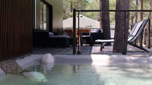 Un espace avec un bain à remous, une terrasse en bois, des chaises longues et une vue sur un bâtiment en arrière-plan.