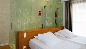 Une chambre d’hôtel avec un lit, deux tables de chevet, un miroir et une fenêtre avec des rideaux.