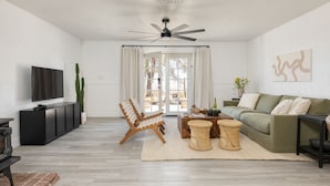 Un salon moderne doté d’un téléviseur à écran plat, d’un ventilateur de plafond, d’un canapé, d’une table basse et d’une table à manger.