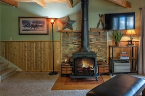 A cozy living room with a fireplace, a television, and a star decoration on the wall.