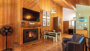 A cozy room with wooden walls, a fireplace, a television, and a sign indicating 'Good Medicine' and 'Unicorn Land'.