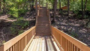 A wooden staircase leading into a forested area.