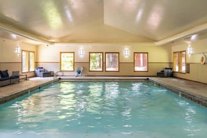 An indoor swimming pool with a tiled floor, a blue chair, and a small table.
