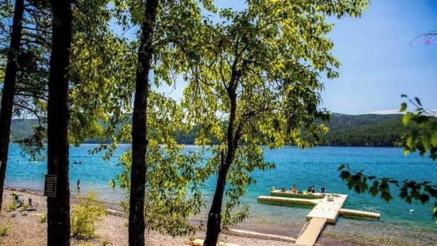 Blick auf einen See mit Steg und Bäumen.