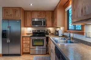 A modern kitchen with wooden cabinets, stainless steel appliances, a built-in oven, and a large window.