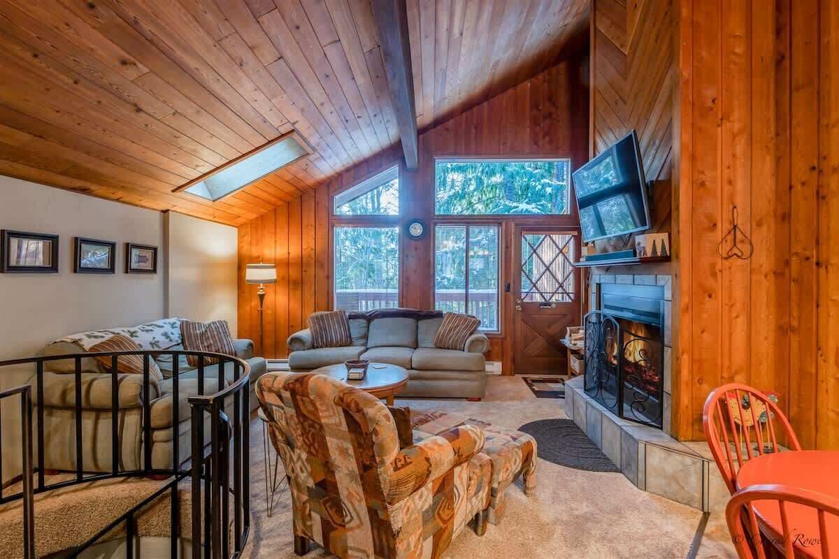 Un intérieur de chalet chaleureux avec une cheminée, des murs en bois et un ensemble de canapés.