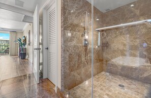 A modern bathroom with a glass-enclosed shower, marble walls, and a view of the outdoors. - Maui Resort Rentals: Honua Kai – Incredible 8 Bedroom Oceanfront Gem, Over 5200 combined Sq. Ft. w/ Built-in Viking B.B.Q.! (Lahaina)