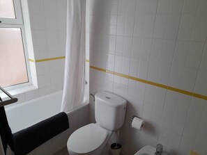 Een bad/douchecombinatie, een haardroger, handdoeken