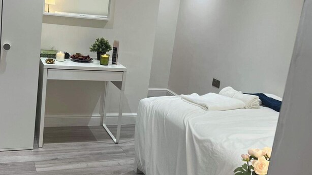 Un dormitorio con cama, un escritorio y una mesita con velas y una planta.