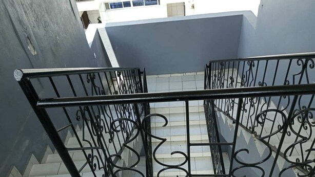 Un escalier orné de rampes en métal noir, menant à l’étage supérieur.