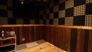 A recording studio with soundproofing panels, a wooden table, and audio equipment. - Glamping Village LEAF (Mashiki)