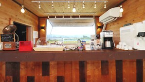 A wooden interior with a counter, coffee machines, a radio, and a view through a window. - Glamping Village LEAF (Mashiki)