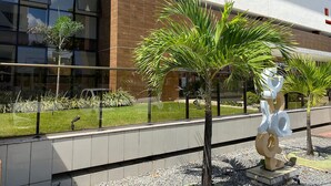 A modern building with glass windows, a tiled ground, and a sculpture.