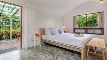 Un dormitorio con cama, mesita de noche y ventana con vistas a zonas verdes.