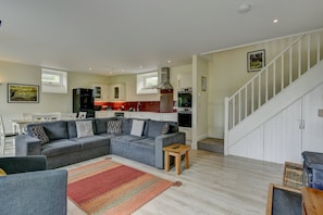 A modern living room with a grey sectional sofa, a small wooden table, and a colorful rug.
