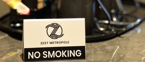 A "NO SMOKING" sign on a countertop with a coffee maker and a kettle.