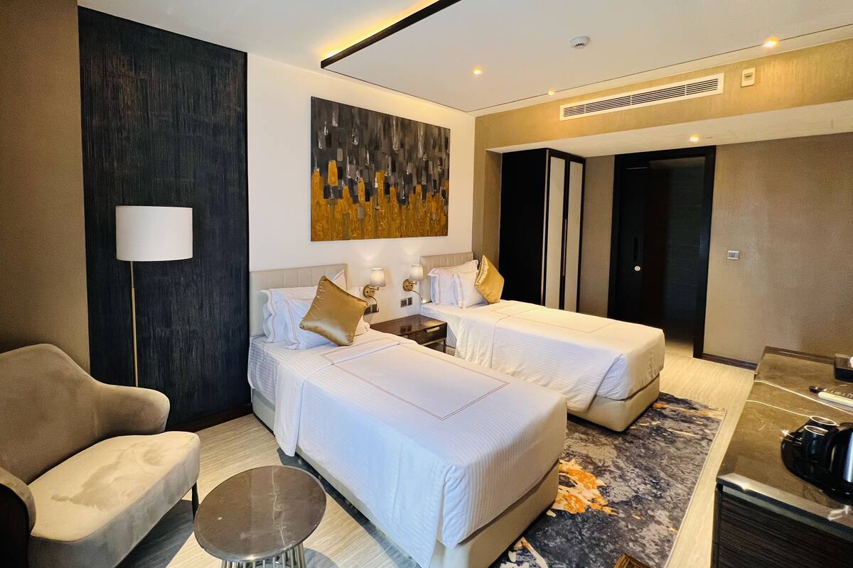 A hotel room with two beds, a sofa, a coffee table, and a painting on the wall.