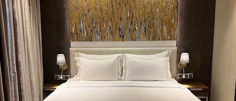 A large bed with a headboard, two bedside tables with lamps, and a textured wall behind.