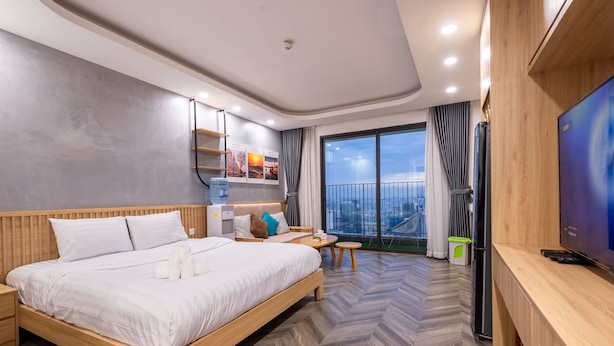 Une chambre d’hôtel moderne dotée d’un grand lit, d’un petit coin salon, d’une télévision et d’un balcon offrant une vue sur la ville.