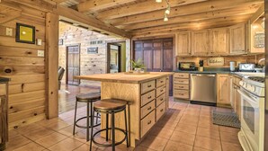 Cocina estilo cabaña de madera con una isla grande, taburetes de bar y electrodomésticos modernos.