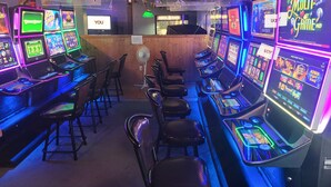 A gaming area with multiple slot machines and a neon sign. - Boyle Motor Inn (Boyle)