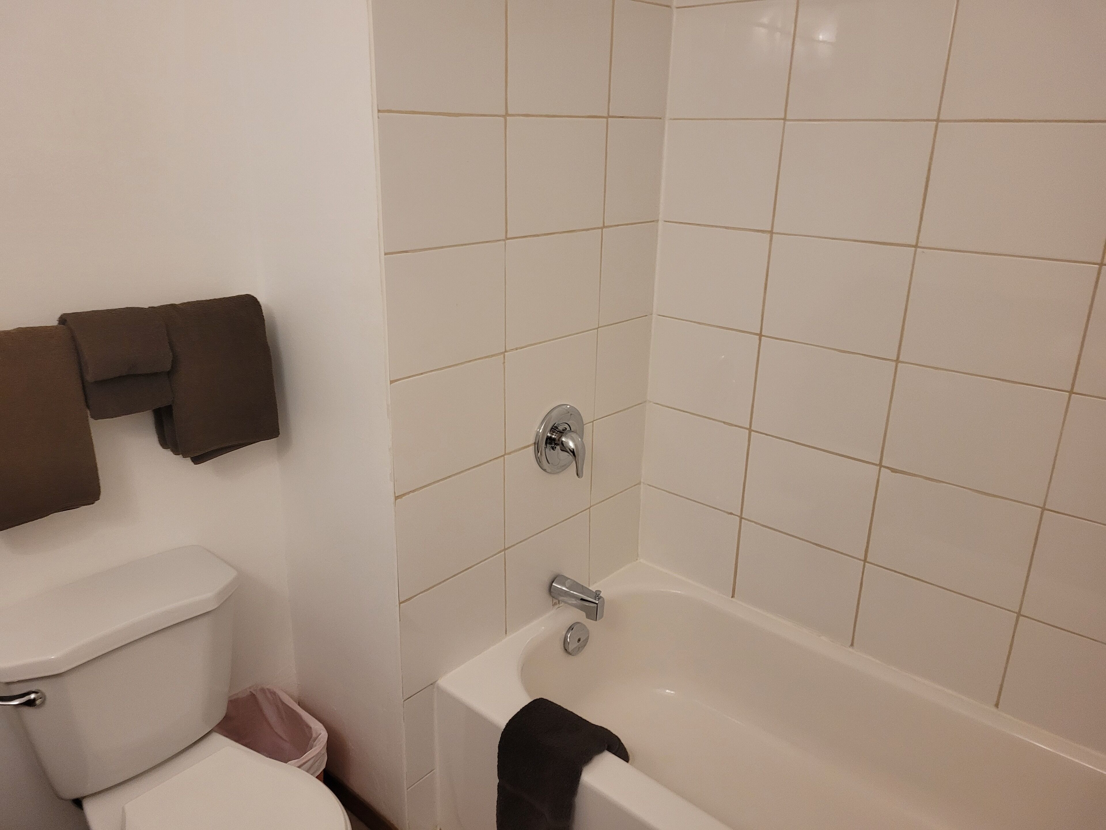 Un baño con inodoro, bañera y un perchero para toallas.
