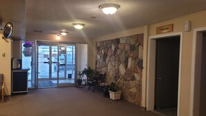 A lobby with a stone wall, a door labeled 'Tavern', and a glass door leading outside. - Boyle Motor Inn (Boyle)