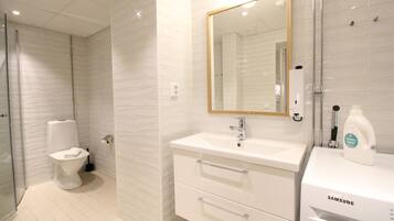 A modern bathroom with a toilet, a sink with a mirror, and a shower area.