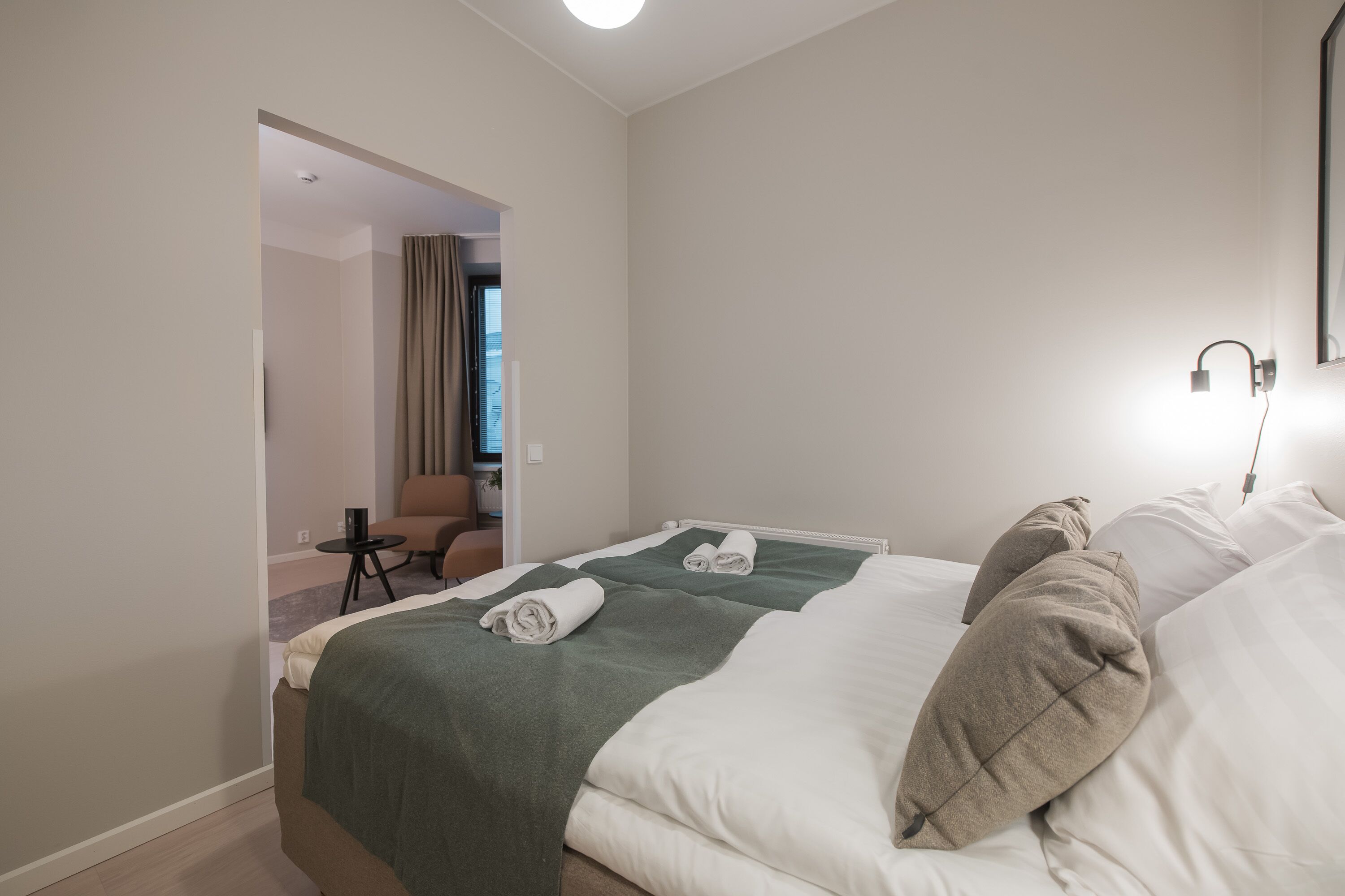 A hotel room with two beds, a small table, and a chair.