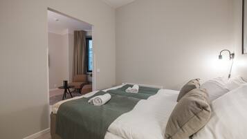 A hotel room with two beds, a small table, and a chair.