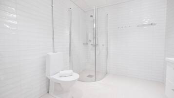 A modern bathroom with a glass-enclosed shower, a white toilet, and a white sink.