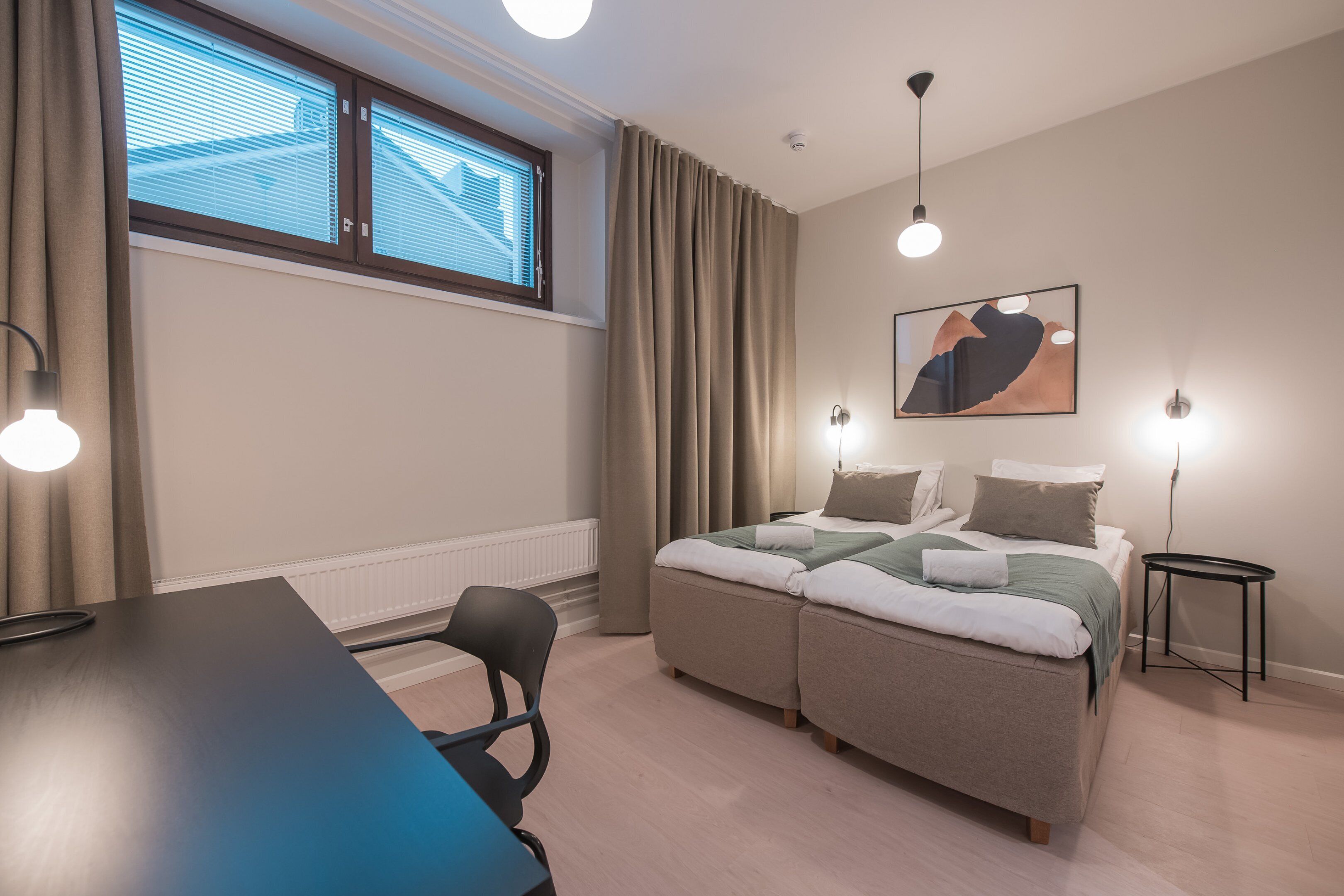 Un dormitorio moderno con cama, mesitas de noche, escritorio y silla.