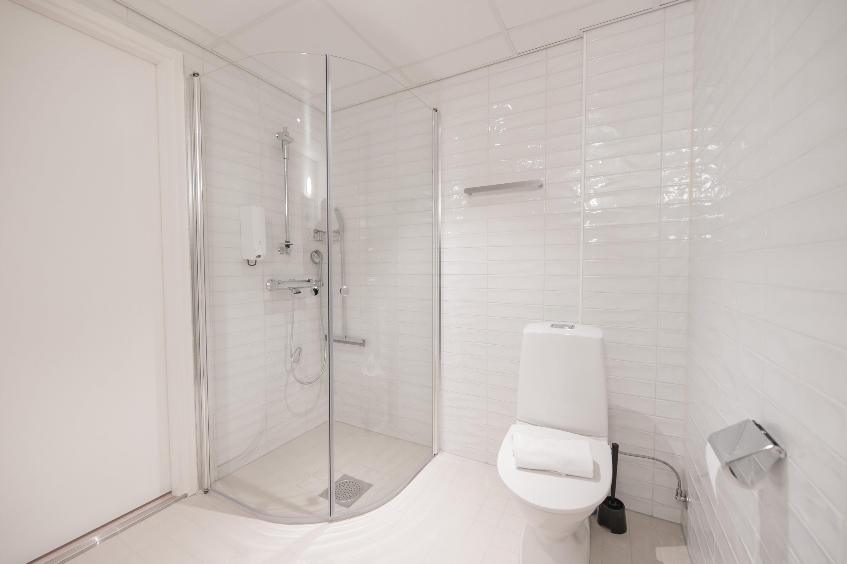 Un baño moderno con ducha de vidrio, inodoro y secador de manos.