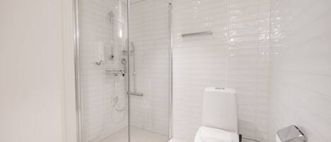 Un baño moderno con ducha de vidrio, inodoro y secador de manos.